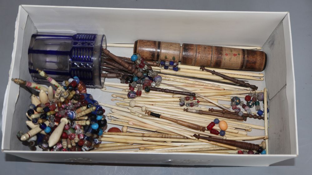 A collection of 19th century glass beaded bone or treen lace bobbins, and bone crochet hooks and knitting needles